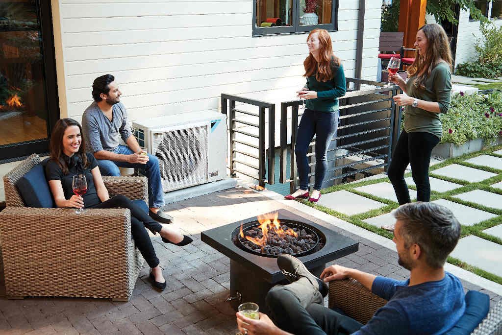 people enjoying patio with DAIKIN FIT heat pump in background