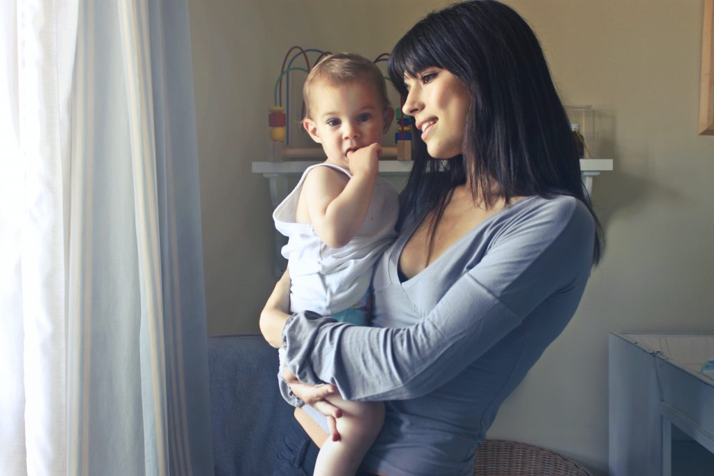 woman looking out window holding a baby