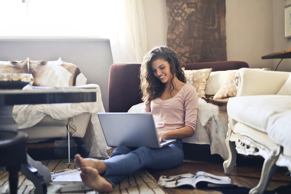 Woman smiling on floor with laptop