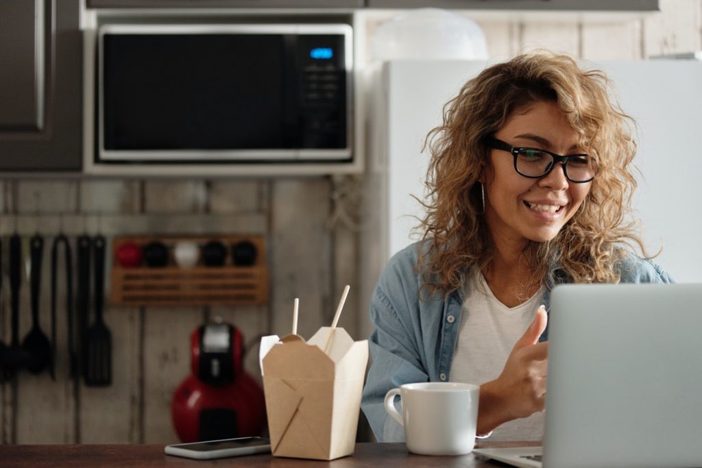 woman sitting in kitchen working on laptop